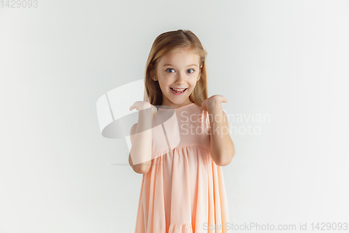 Image of Little smiling girl posing in dress on white studio background