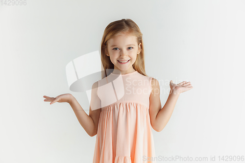 Image of Little smiling girl posing in dress on white studio background