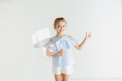 Image of Little smiling girl posing in casual clothes on white studio background