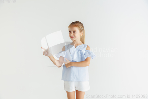 Image of Little smiling girl posing in casual clothes on white studio background