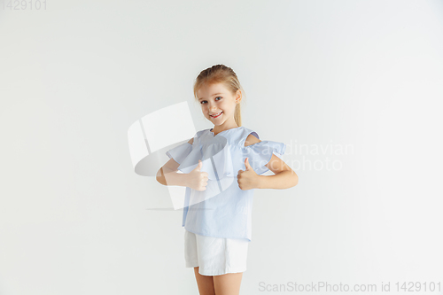Image of Little smiling girl posing in casual clothes on white studio background