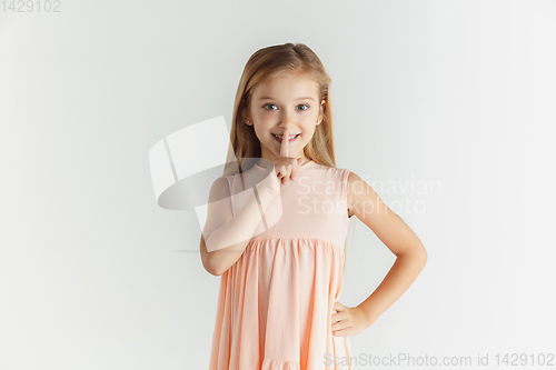 Image of Little smiling girl posing in dress on white studio background