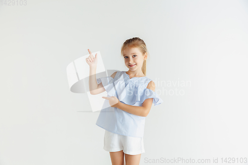 Image of Little smiling girl posing in casual clothes on white studio background