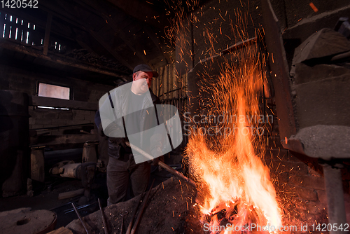 Image of young traditional Blacksmith working with open fire