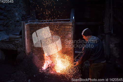 Image of young traditional Blacksmith working with open fire