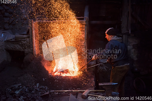 Image of young traditional Blacksmith working with open fire