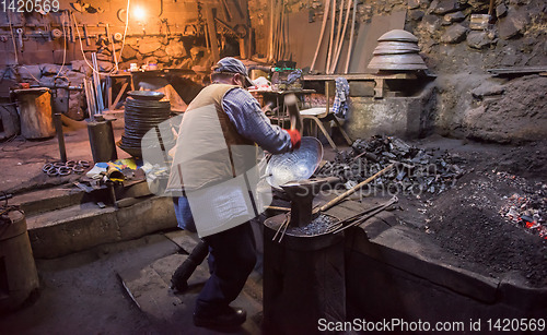 Image of traditional blacksmith manually forging the molten metal