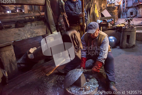 Image of blacksmith workers using mechanical hammer at workshop