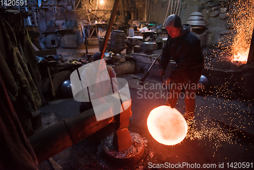 Image of blacksmith workers using mechanical hammer at workshop