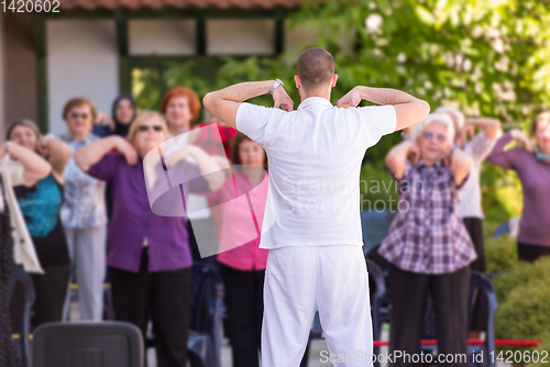 Image of trainer training motivated active healthy senior people