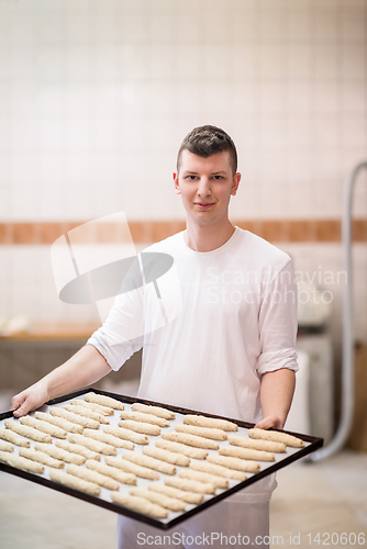 Image of A young baker holding raw product of white dough
