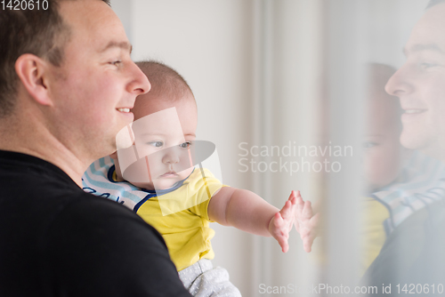 Image of young father holding baby near the window at home