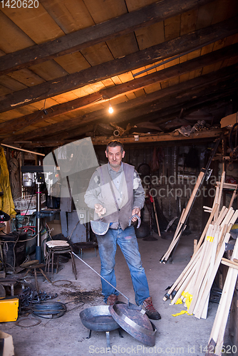 Image of A blacksmith worker showing handmade products ready for sale