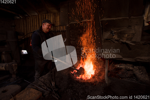 Image of young traditional Blacksmith working with open fire