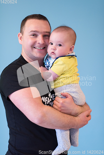 Image of portrait of happy young father holding baby isolated on blue