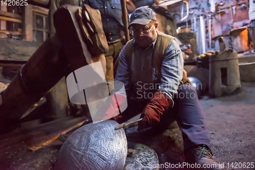 Image of blacksmith workers using mechanical hammer at workshop