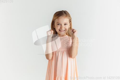 Image of Little smiling girl posing in dress on white studio background