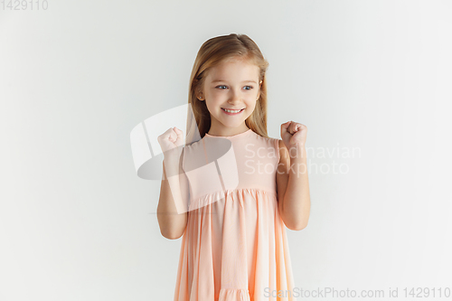 Image of Little smiling girl posing in dress on white studio background