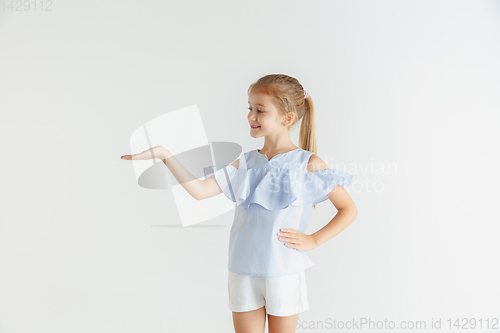 Image of Little smiling girl posing in casual clothes on white studio background