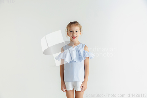 Image of Little smiling girl posing in casual clothes on white studio background