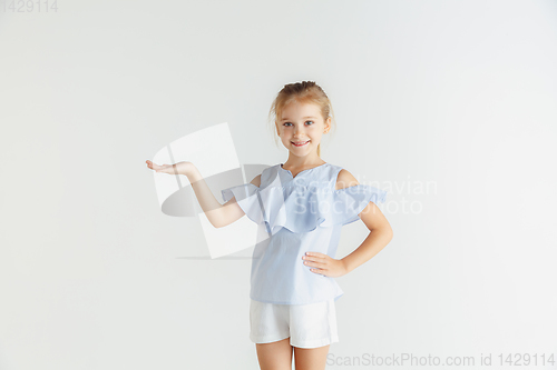 Image of Little smiling girl posing in casual clothes on white studio background