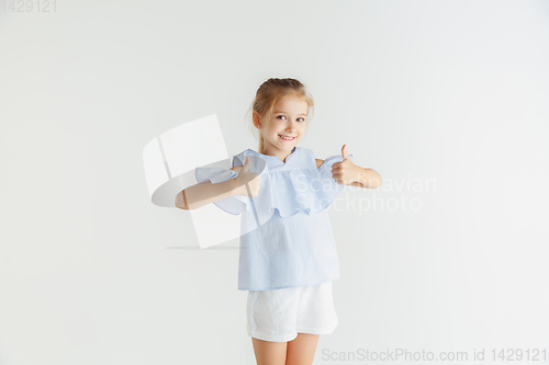 Image of Little smiling girl posing in casual clothes on white studio background