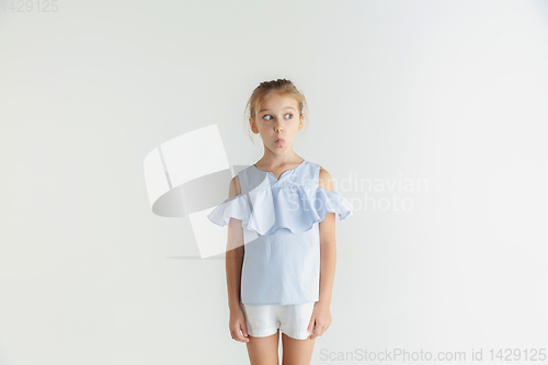 Image of Little smiling girl posing in casual clothes on white studio background