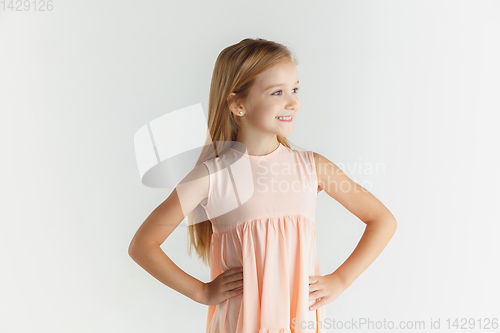 Image of Little smiling girl posing in dress on white studio background