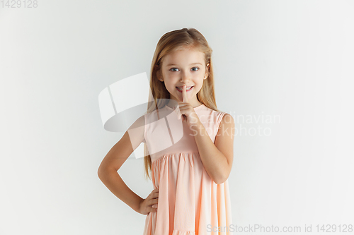 Image of Little smiling girl posing in dress on white studio background
