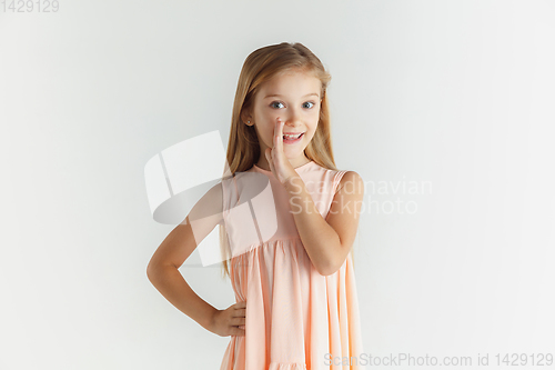 Image of Little smiling girl posing in dress on white studio background