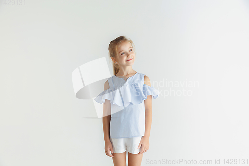 Image of Little smiling girl posing in casual clothes on white studio background