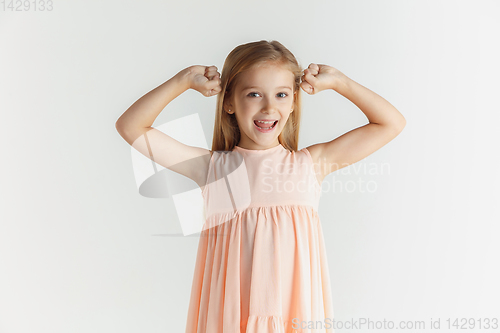 Image of Little smiling girl posing in dress on white studio background