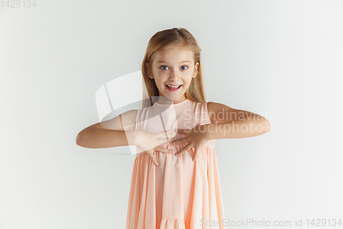 Image of Little smiling girl posing in dress on white studio background