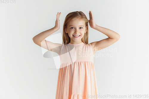 Image of Little smiling girl posing in dress on white studio background