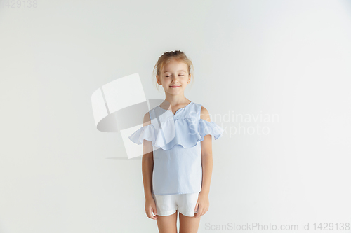 Image of Little smiling girl posing in casual clothes on white studio background