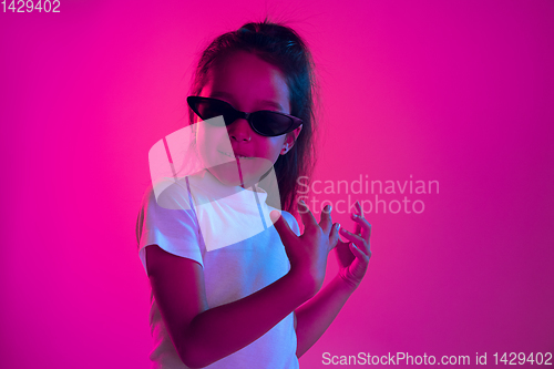 Image of Portrait of little girl in headphones on purple gradient background in neon light