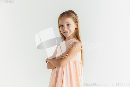 Image of Little smiling girl posing in dress on white studio background