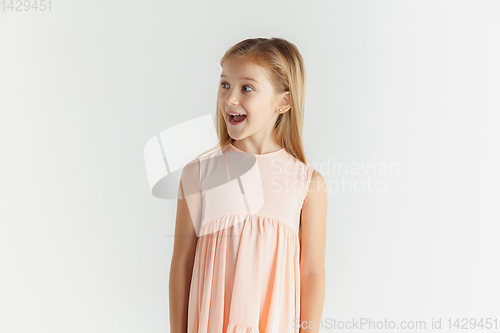 Image of Little smiling girl posing in dress on white studio background