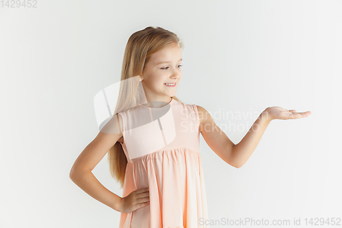 Image of Little smiling girl posing in dress on white studio background