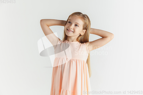 Image of Little smiling girl posing in dress on white studio background