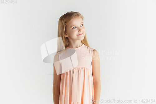 Image of Little smiling girl posing in dress on white studio background