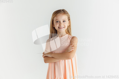 Image of Little smiling girl posing in dress on white studio background