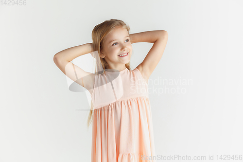 Image of Little smiling girl posing in dress on white studio background