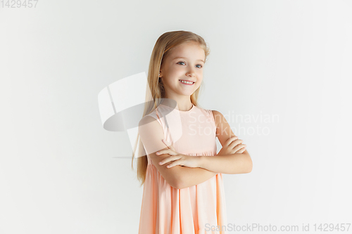Image of Little smiling girl posing in dress on white studio background