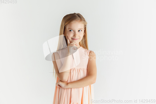 Image of Little smiling girl posing in dress on white studio background