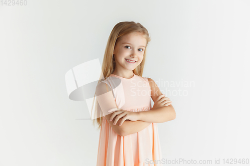 Image of Little smiling girl posing in dress on white studio background