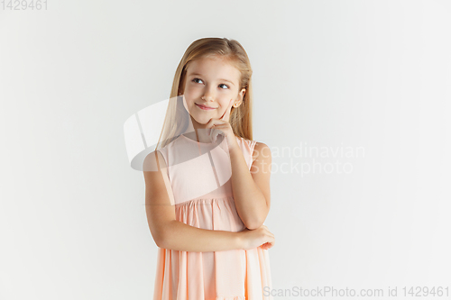 Image of Little smiling girl posing in dress on white studio background