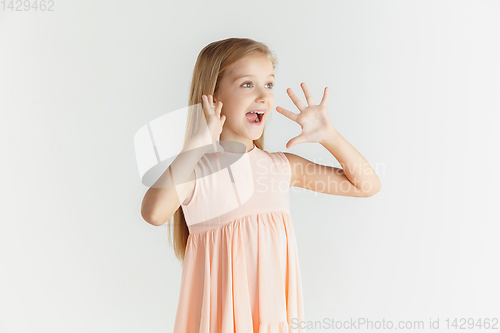 Image of Little smiling girl posing in dress on white studio background