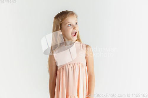 Image of Little smiling girl posing in dress on white studio background