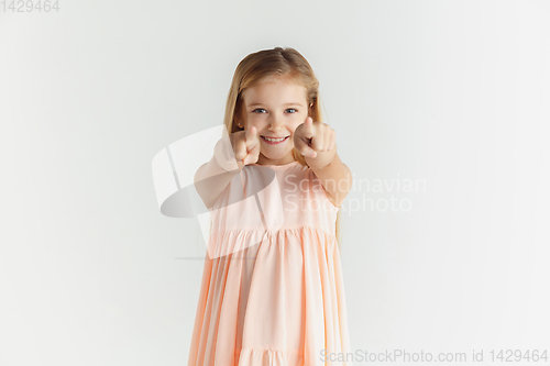 Image of Little smiling girl posing in dress on white studio background